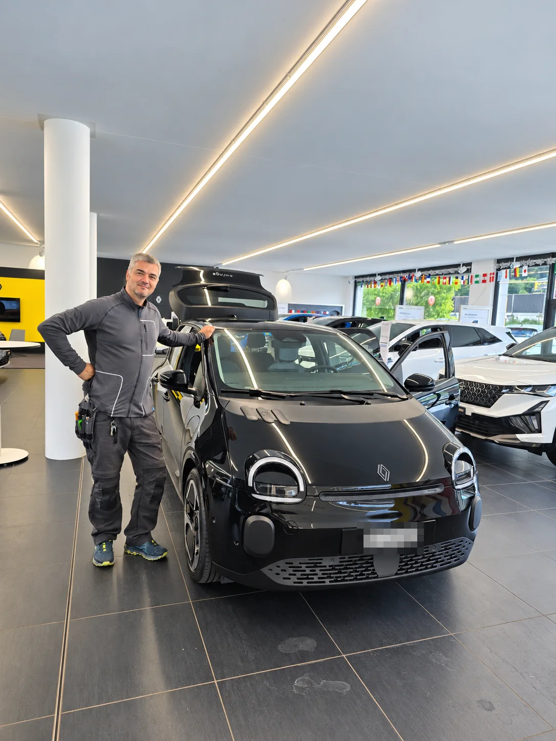 Nijaz neben dem neuen Renault Twingo im Autohaus